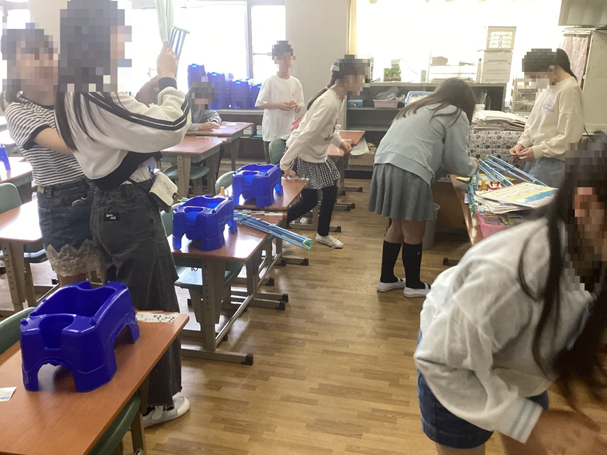 1年生の教室で朝顔の植木鉢を準備する6年生の児童たち