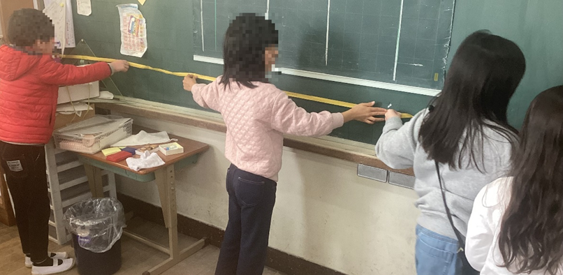 黒板に長さテープを広げる児童