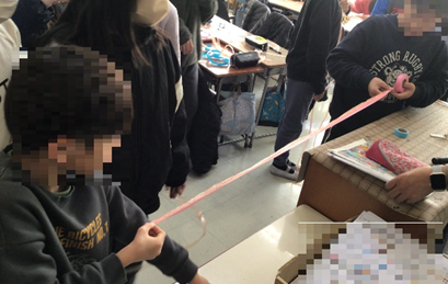 テープを伸ばす児童